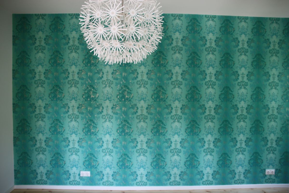 Ein Raum mit grüner Tapete und einem weißen Kronleuchter, der von der Decke hängt.