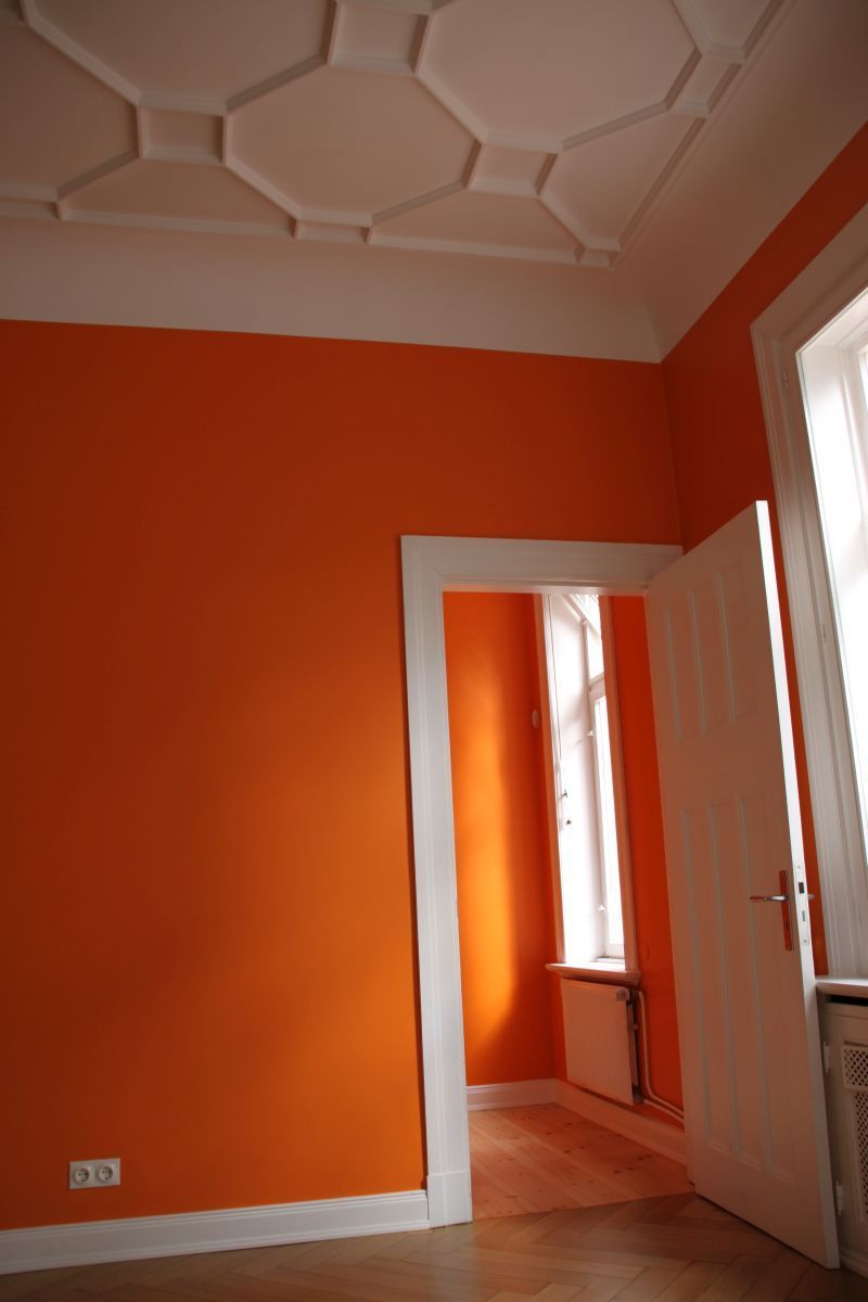 Ein Raum mit orangefarbenen Wänden und einer weißen Tür