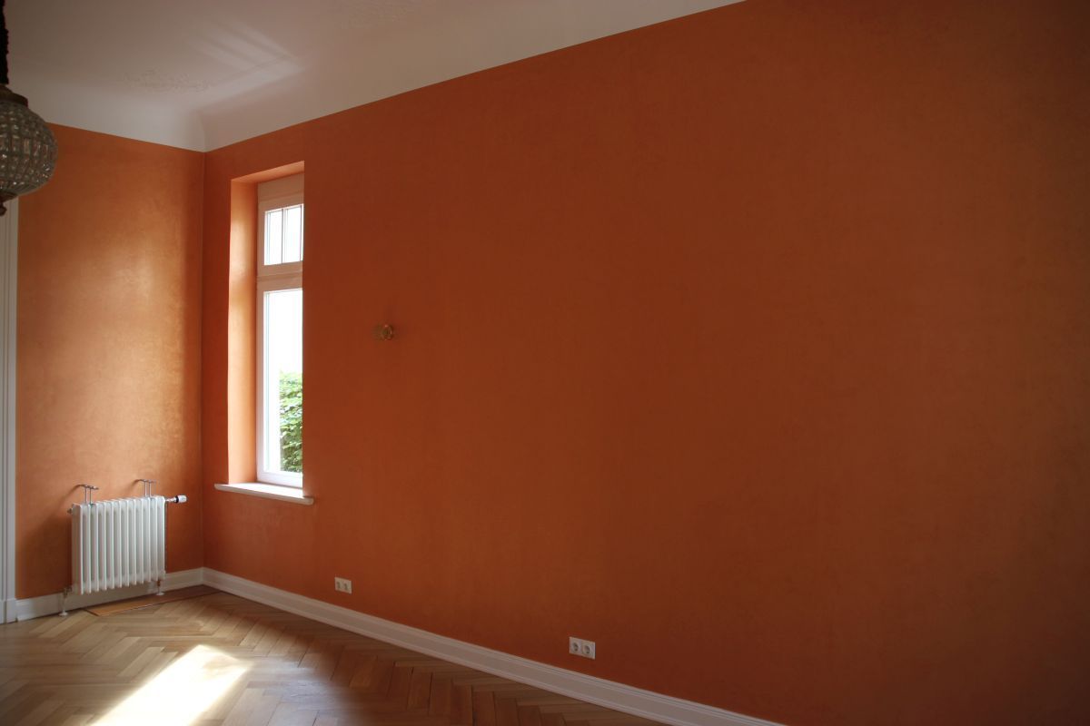 Ein leerer Raum mit orangefarbenen Wänden und einem Fenster.