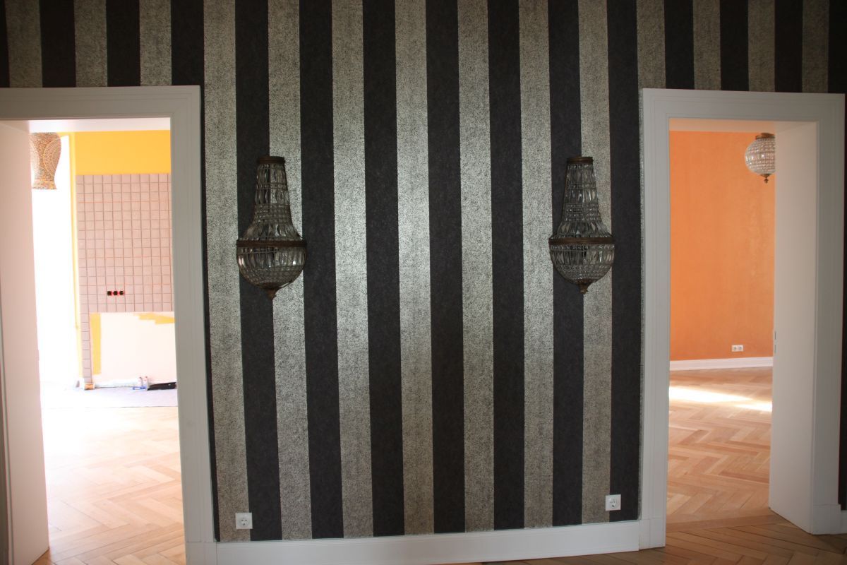 Ein Raum mit gestreifter Wand und zwei Kronleuchtern an der Wand