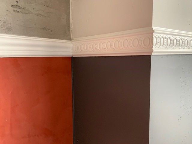 Eine Zimmerecke mit zwei verschiedenfarbigen Wänden und einer weißen Zierleiste
