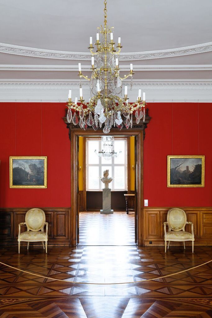 Ein Raum mit roten Wänden und einem Kronleuchter, der von der Decke hängt