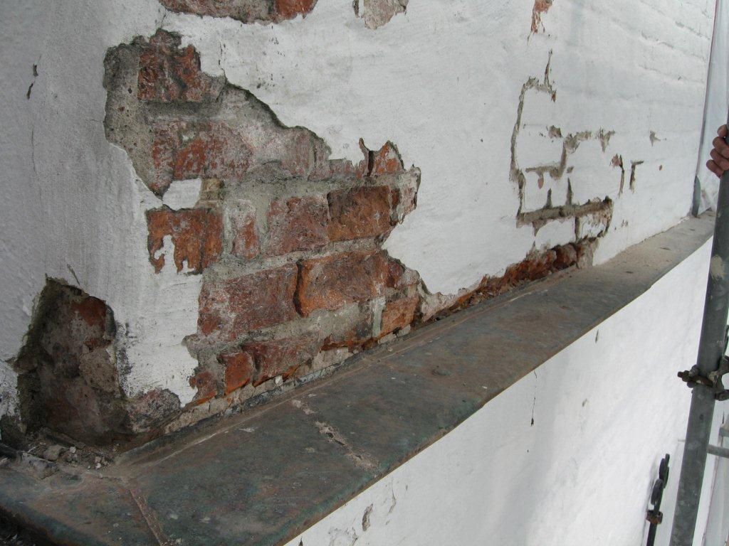 Eine weiße Wand mit Ziegeln darauf und eine Person steht daneben