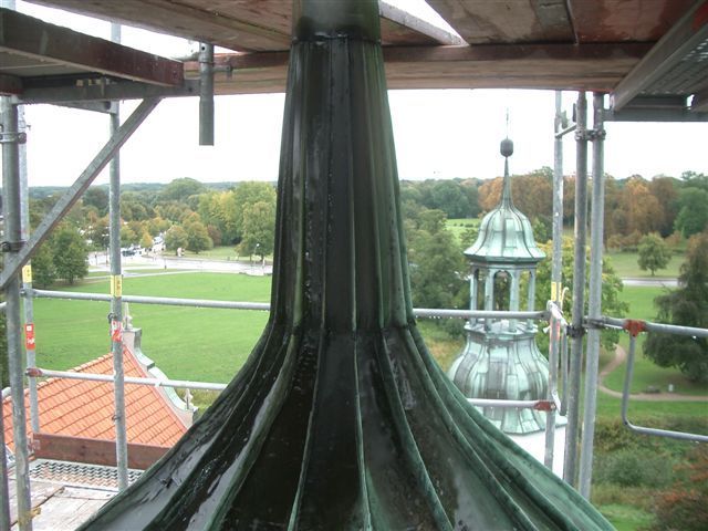 Ein sehr hohes Gebäude mit Gerüsten darum herum und einem Park im Hintergrund