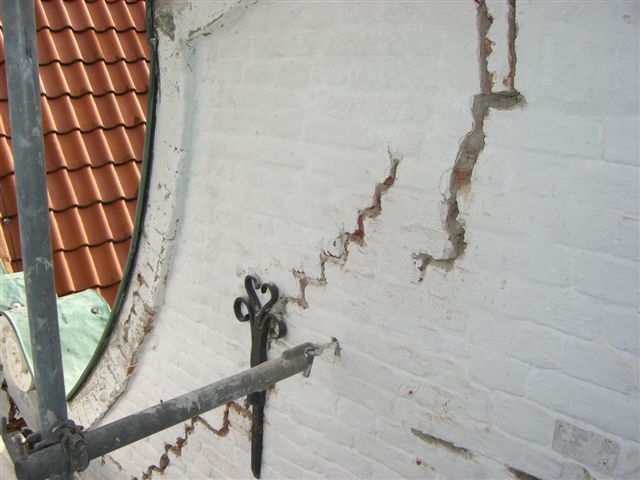 Eine Ziegelwand mit einem Loch darin und einem Gerüst davor