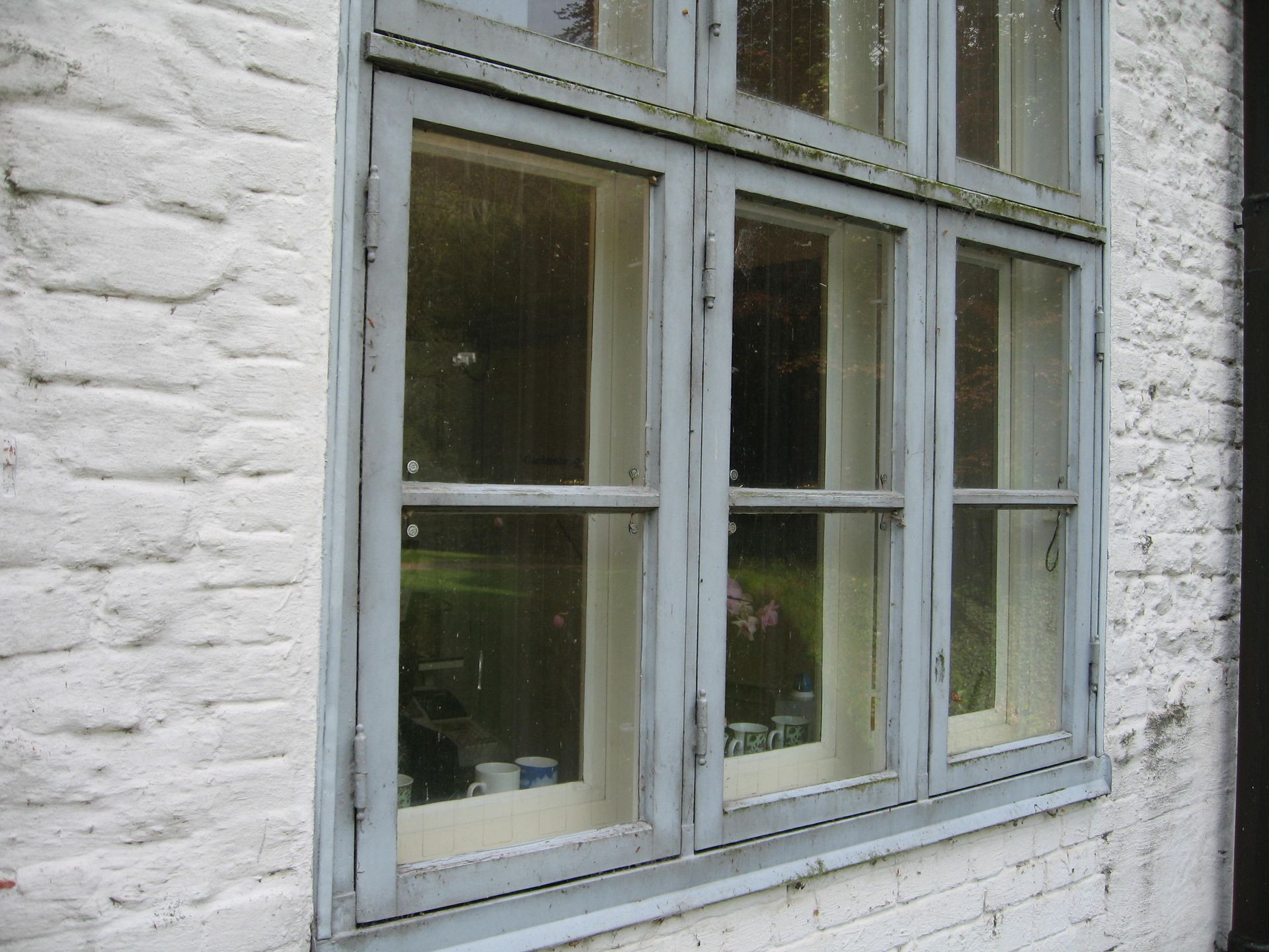 Ein weißes Backsteingebäude mit einem blauen Fenster