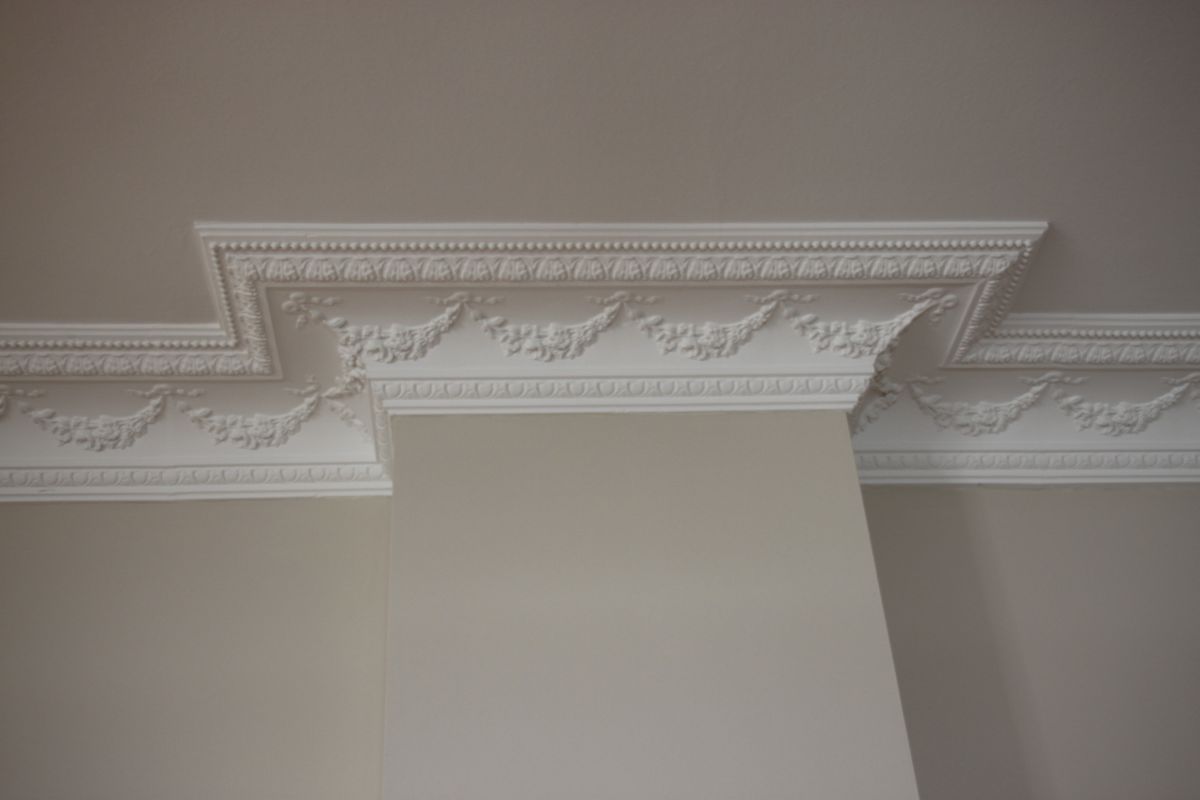 Eine Nahaufnahme einer weißen Zierleiste an der Decke eines Raumes.