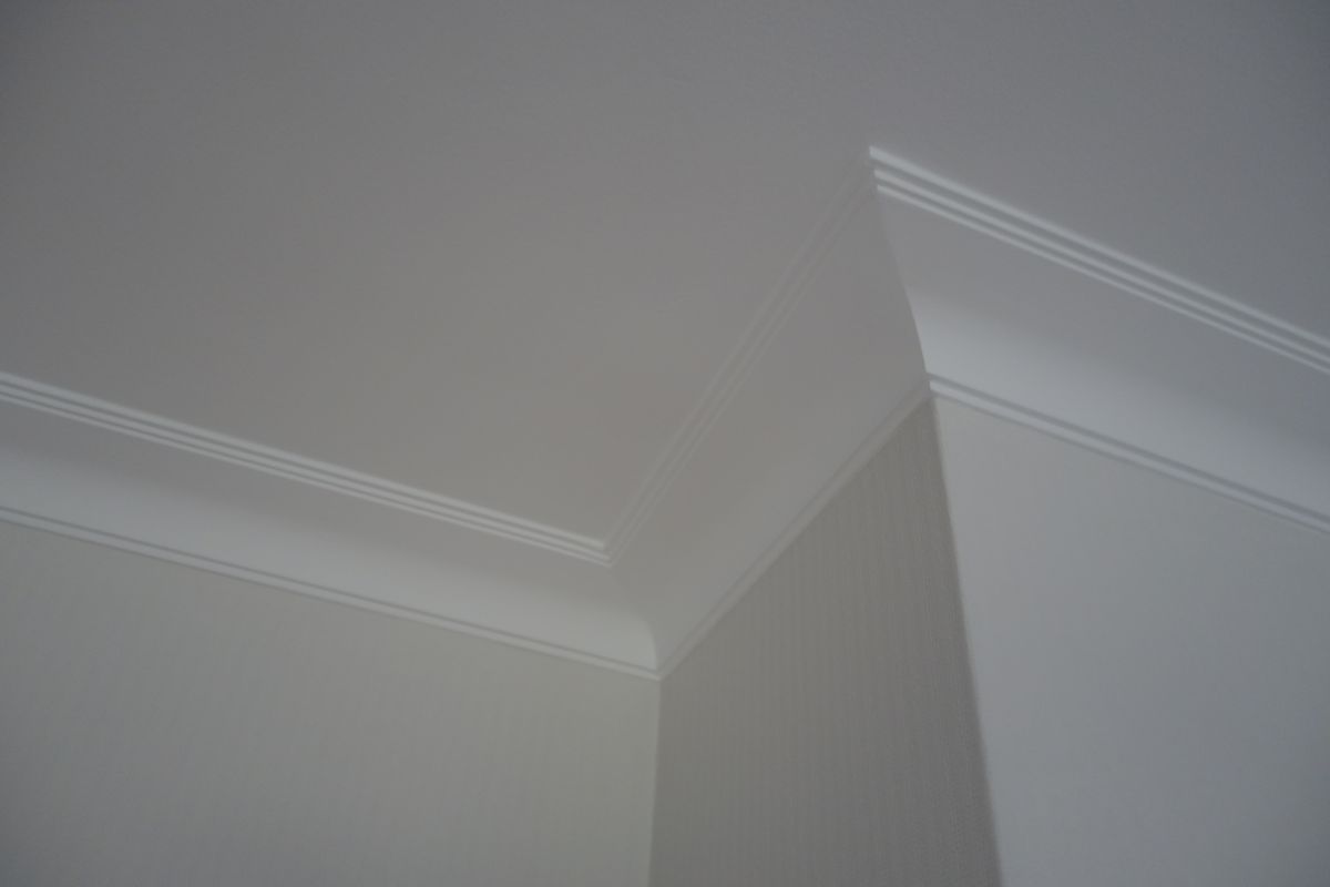 Eine Nahaufnahme einer weißen Wand und Decke mit Zierleiste.