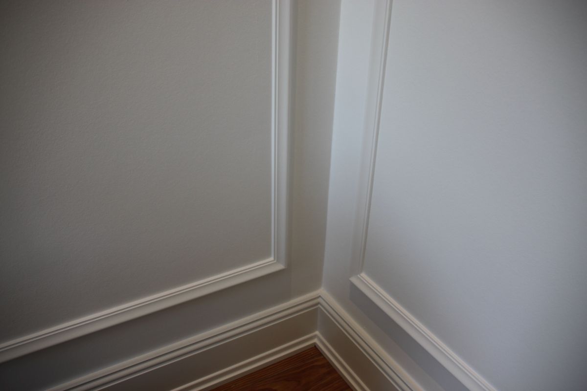 Eine Zimmerecke mit weißen Wänden und Zierleisten.