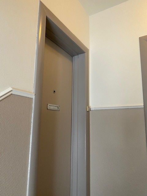 Ein Flur mit einer grauen Tür und weißen Wänden