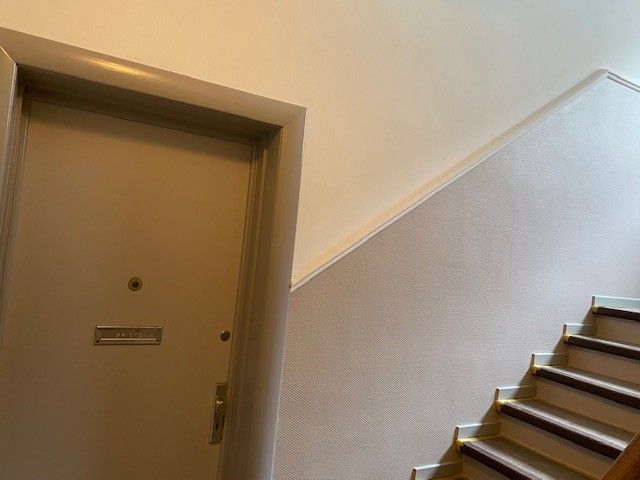 Eine Tür in einem Flur neben einer Treppe.