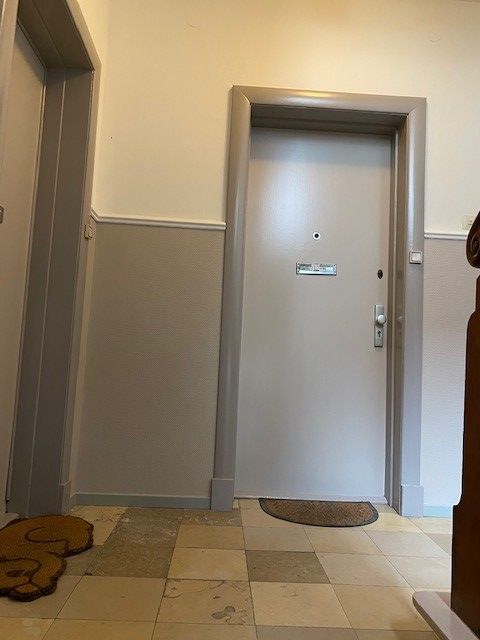 Ein Flur mit einer Tür und einem Teppich auf dem Boden.