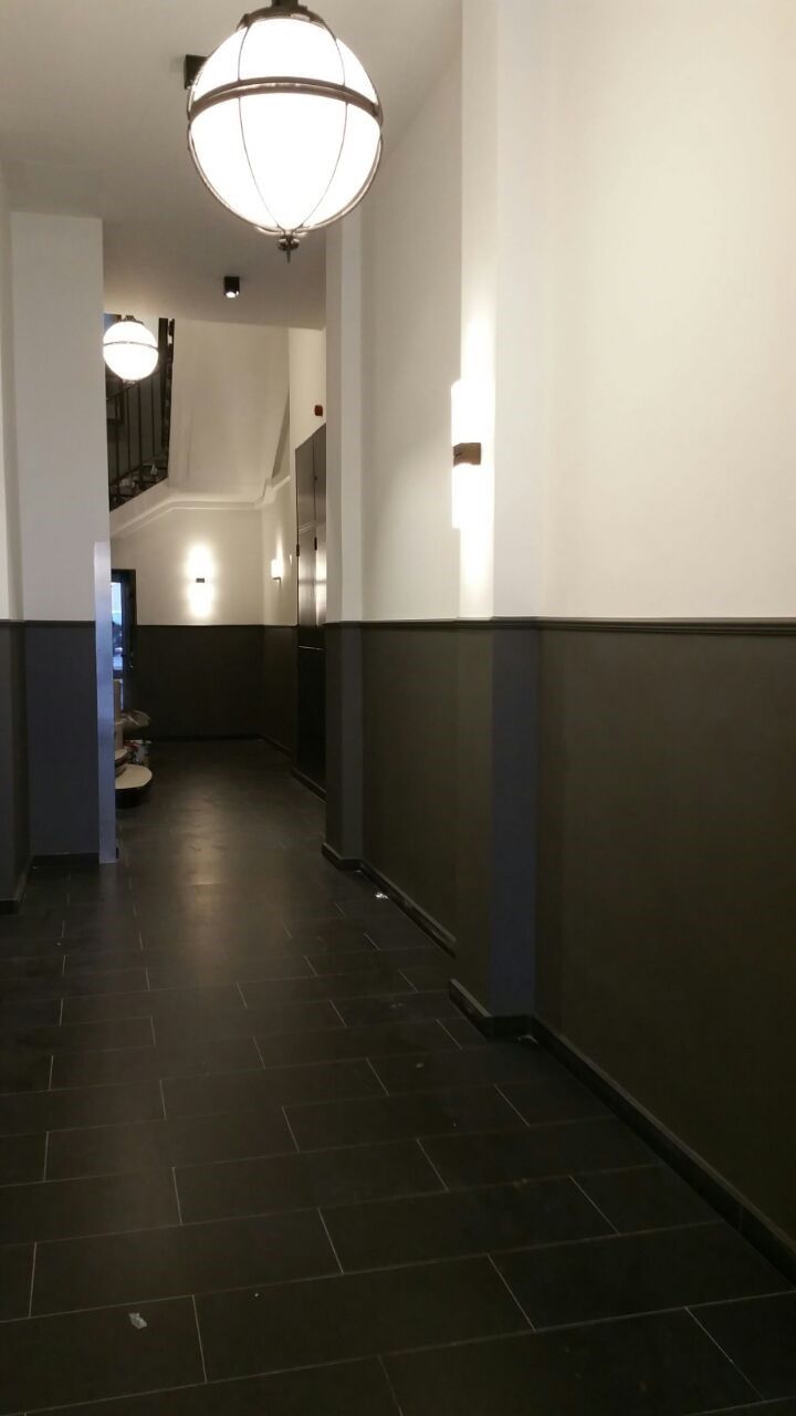 Ein langer Flur mit schwarzem Fliesenboden und weißen Wänden.