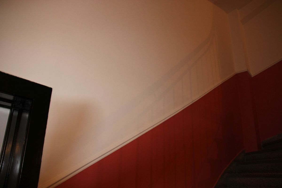 Eine rot-weiße Wand mit einer schwarzen Tür im Hintergrund