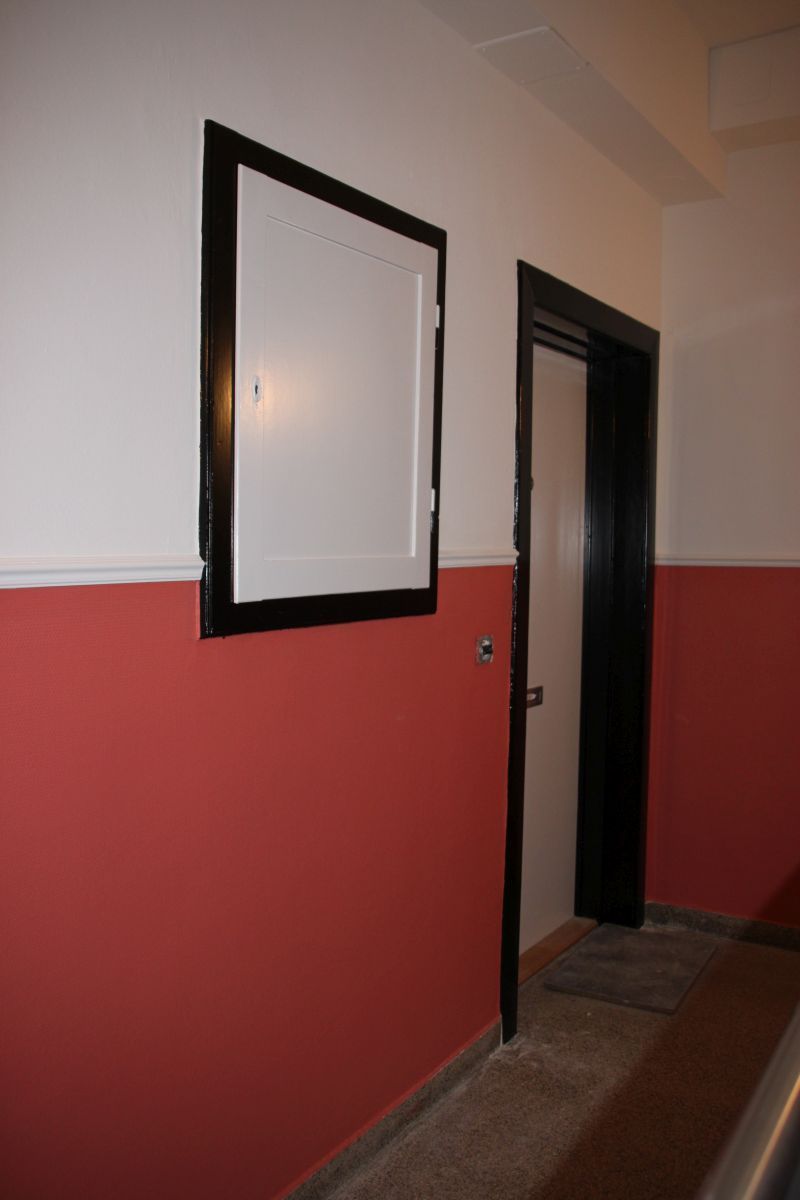 Ein Flur mit roten und weißen Wänden und einer schwarzen Tür