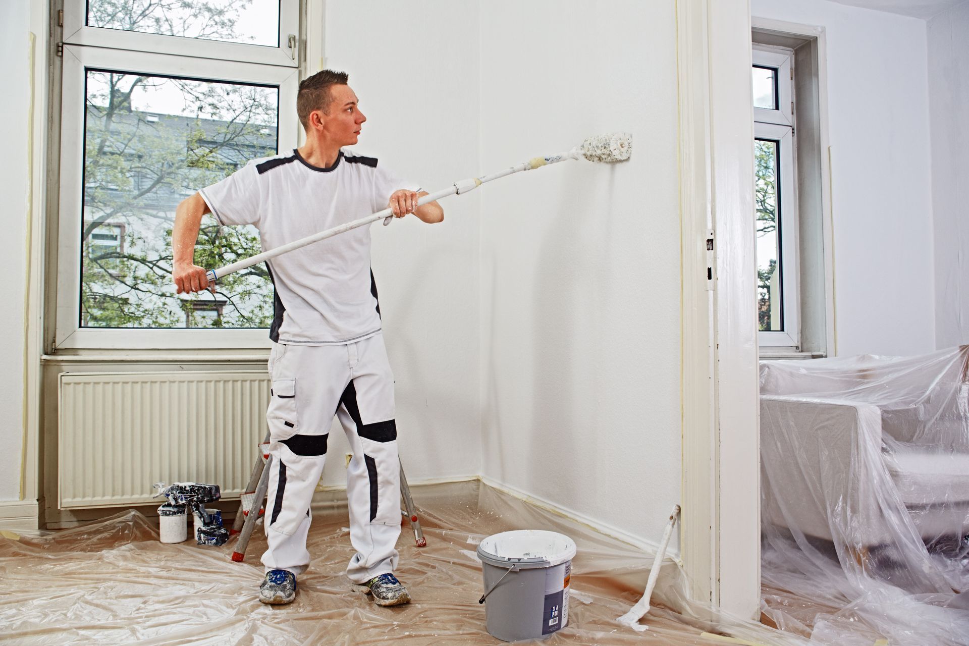 Handwerker streicht Wand mit Malerrolle nach professioneller Schimmelsanierung in Hamburg Wandbek