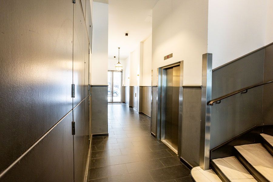 Ein langer Flur mit Treppen und Aufzügen in einem Gebäude.