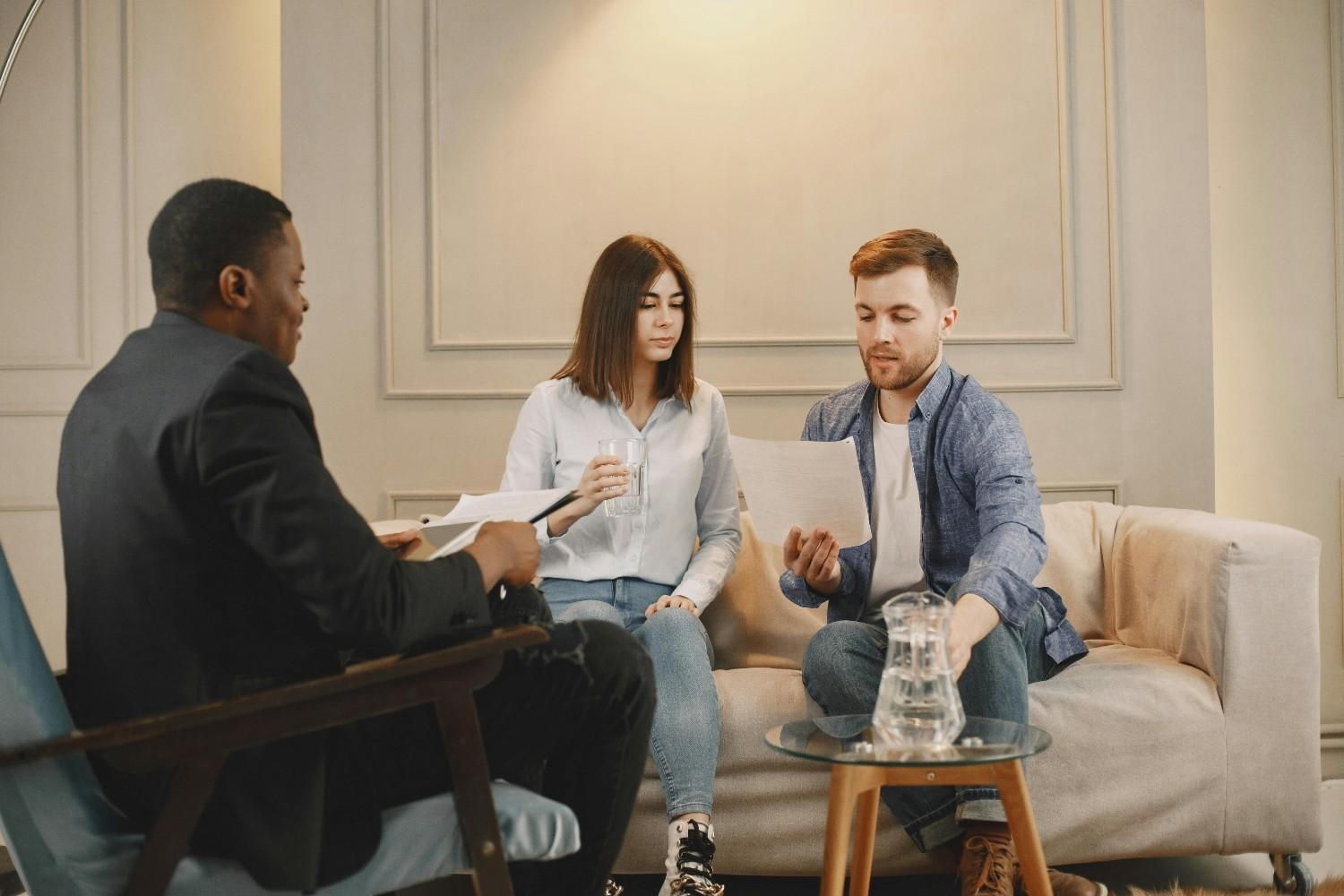 Tres personas en una sesión de terapia, sentadas en una luminosa sala de estar, conversando mientras toman café.