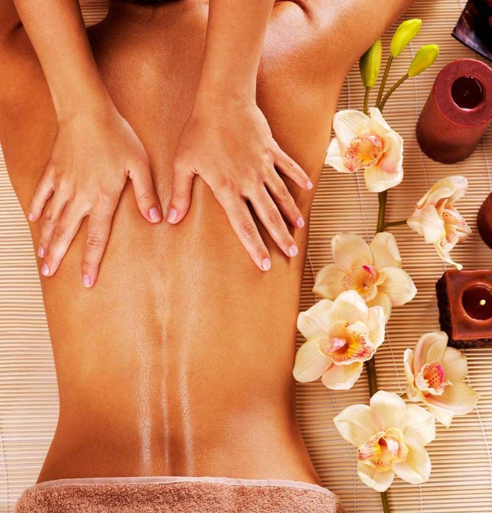 Une femme reçoit un massage avec des fleurs et des bougies en arrière-plan