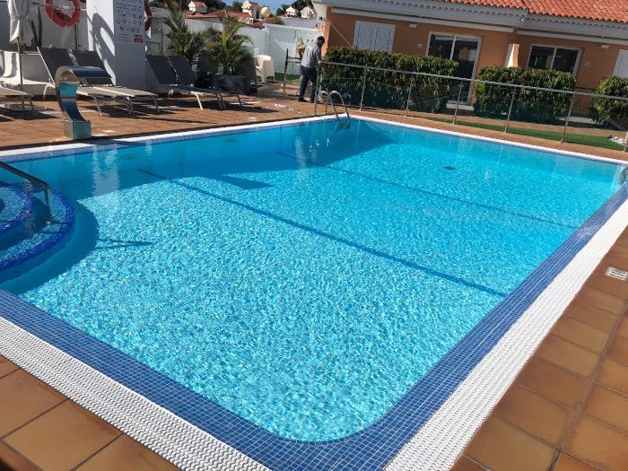 Un hombre está de pie junto a una gran piscina.