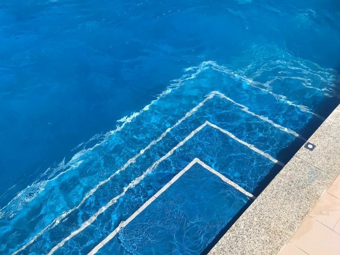 Una piscina con agua azul y escalones blancos.