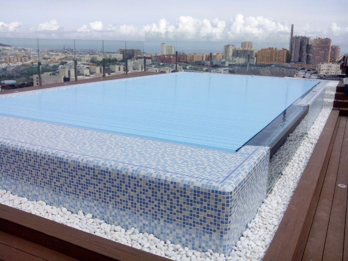Una gran piscina en lo alto de un edificio con una ciudad al fondo.