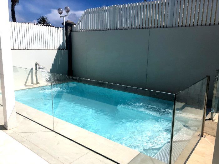 Una piscina con una valla de cristal a su alrededor.