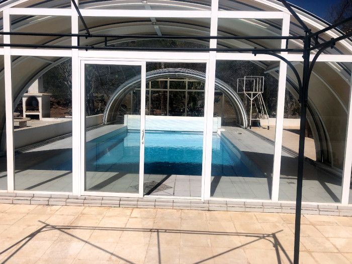 Una gran piscina está detrás de un recinto de cristal.