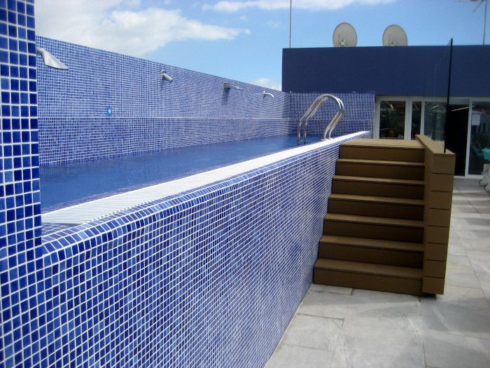 Una piscina con azulejos azules y escaleras que conducen a ella.