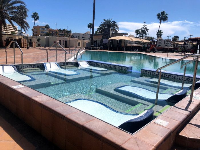 Una gran piscina con muchas tumbonas.