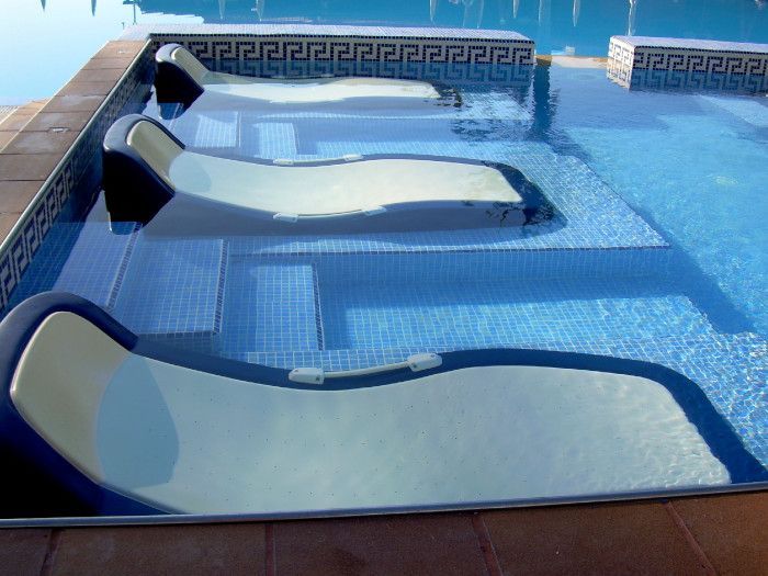 Una fila de sillas de salón junto a una piscina.