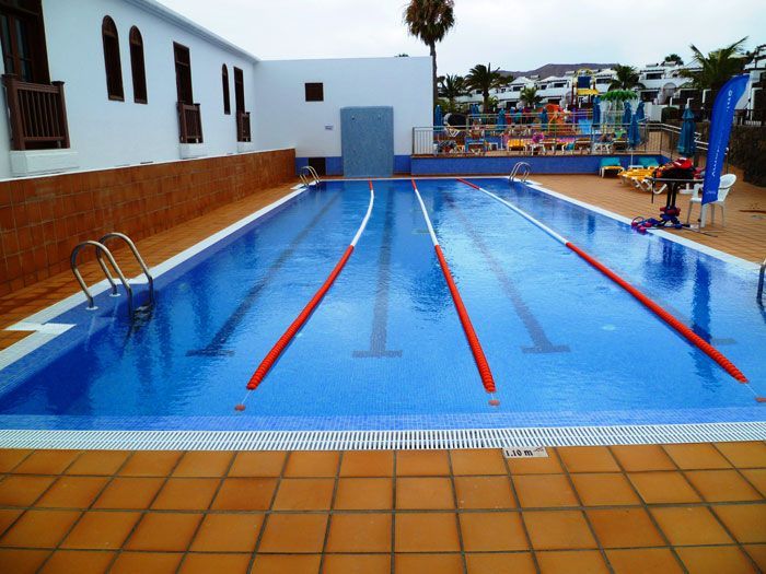 Una gran piscina con carriles rojos y un edificio blanco al fondo.