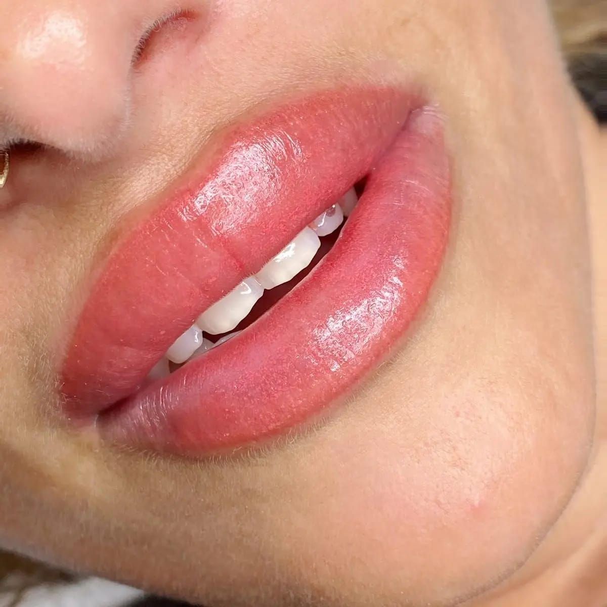 Eine Nahaufnahme des Mundes einer Frau mit rosa Lippen und weißen Zähnen.