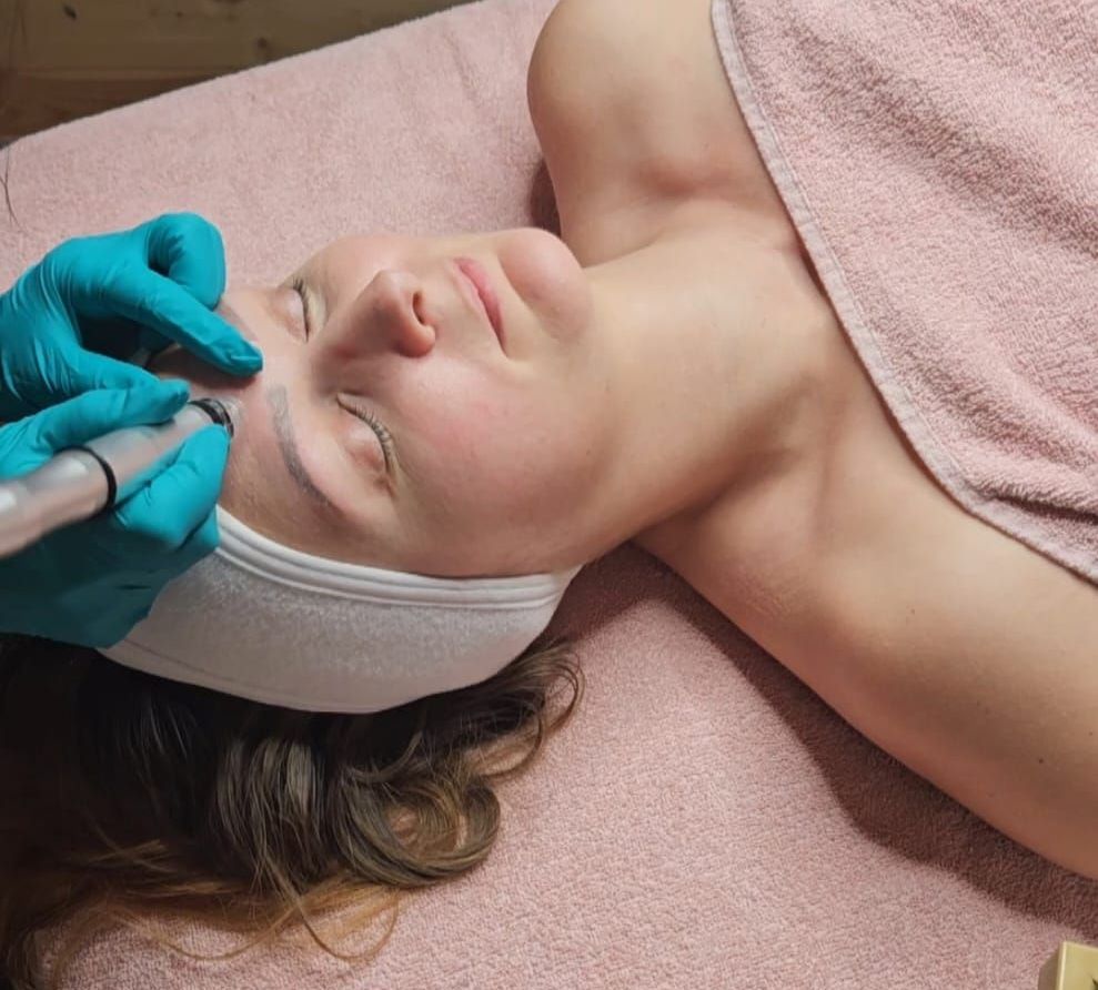 Eine Frau liegt auf einem Bett und bekommt eine Gesichtsbehandlung.