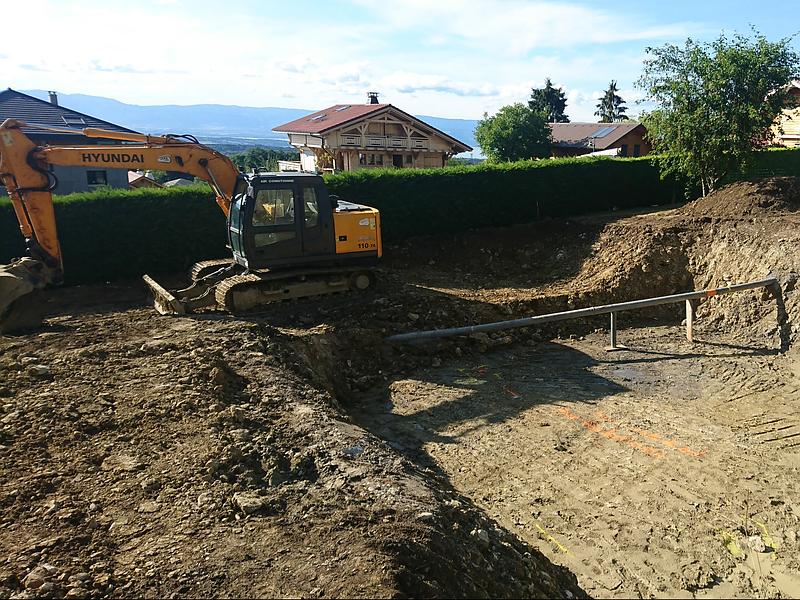 Une excavatrice creuse une fosse de construction dans une cour