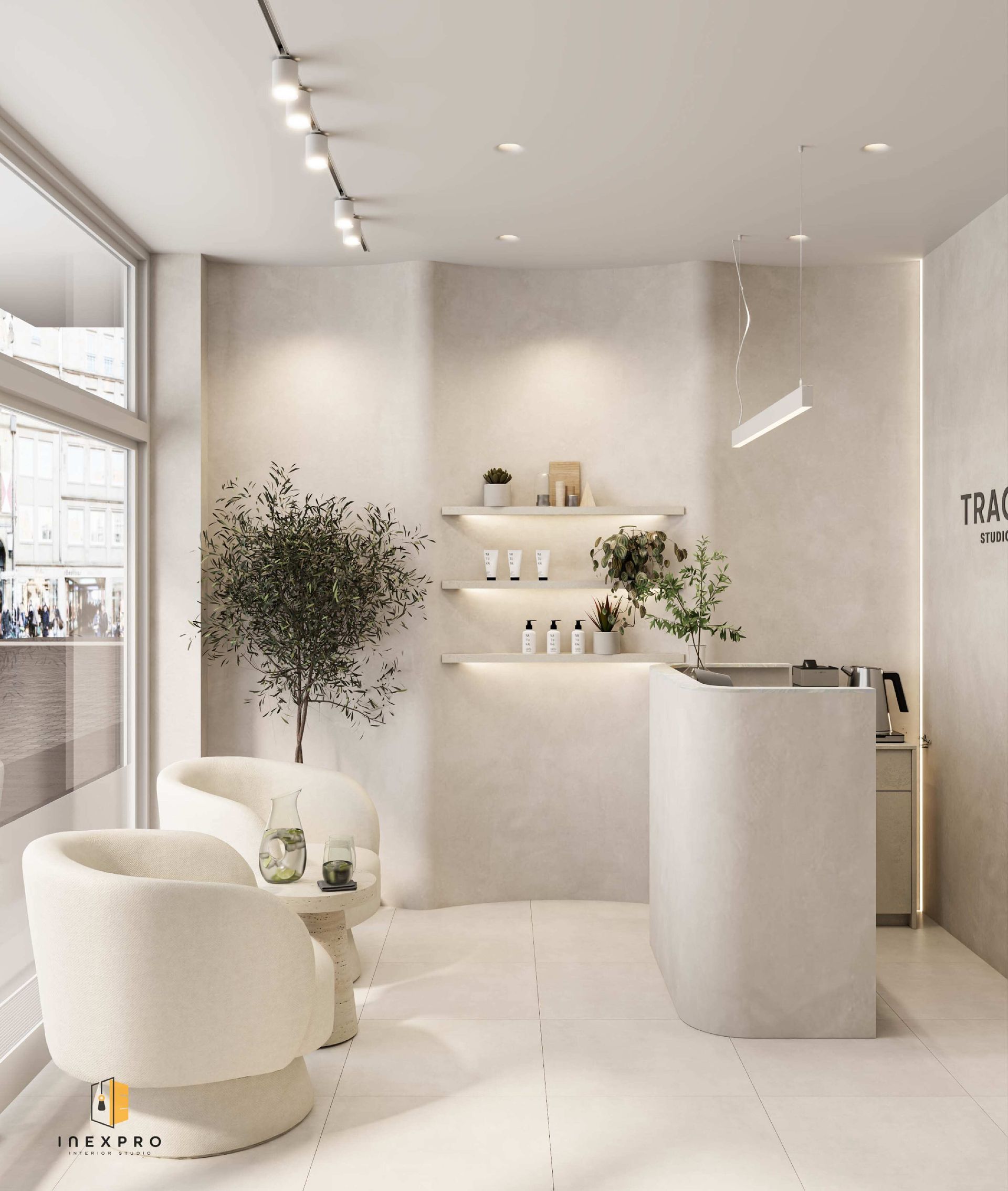 Cremefarbener Spa-Innenraum mit geschwungenem Empfangstresen, zwei Sesseln, kleinem Baum und minimalistischer Dekoration.