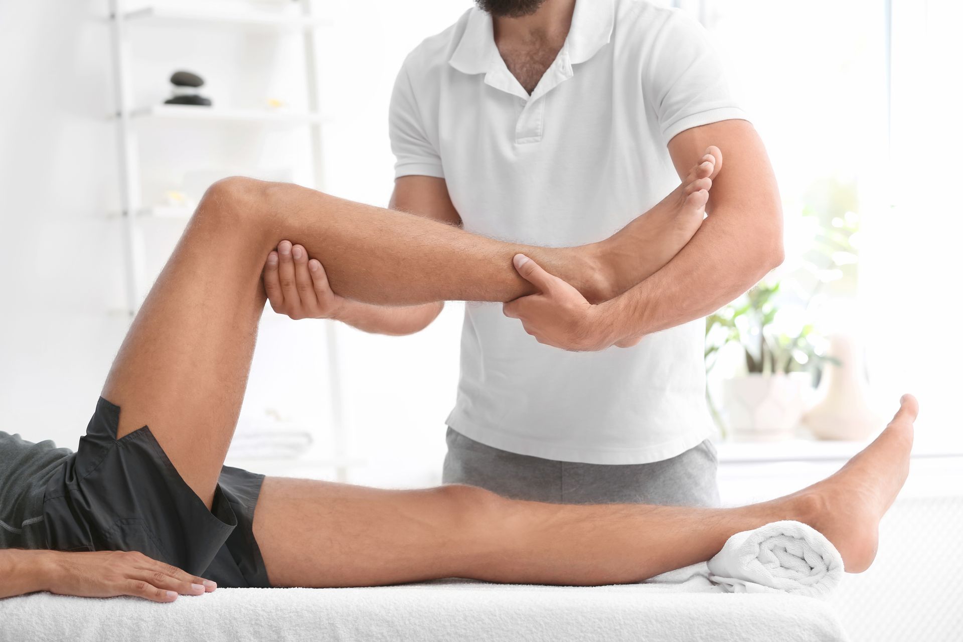 Un homme en short se fait examiner la jambe par un médecin, à l'intérieur, pour une thérapie physique.