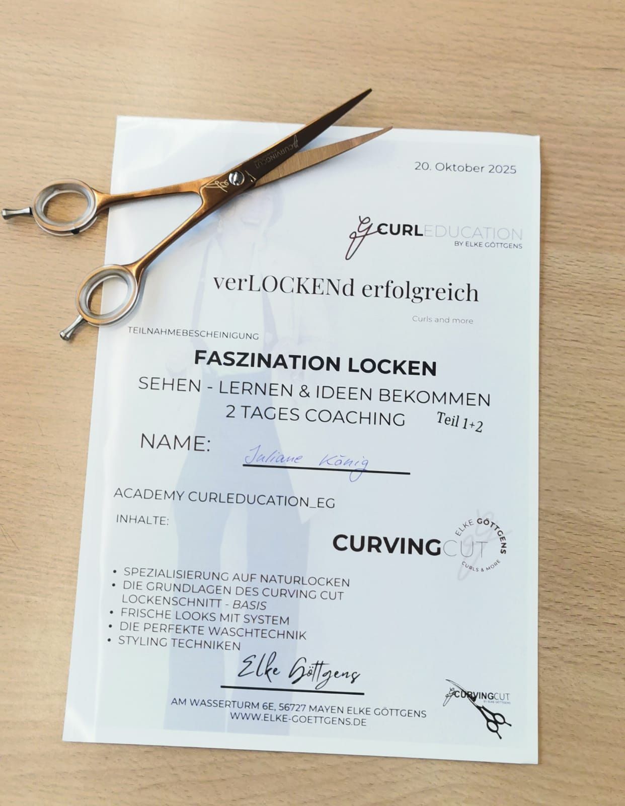 Schere auf einem Zertifikat mit dem Titel „Faszinierende Curls“ für einen zweitägigen Curling-Trainerkurs.