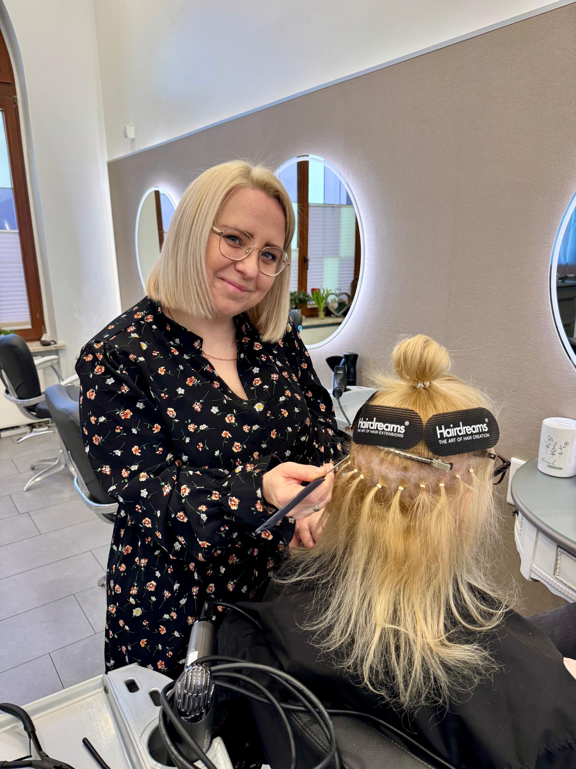 Blonde Frau stylt sich in einem Salon mit einem Kamm die blonden Haare.