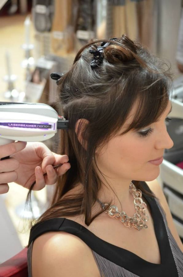 Eine Frau lässt sich von einer Stylistin Haarverlängerungen anbringen.