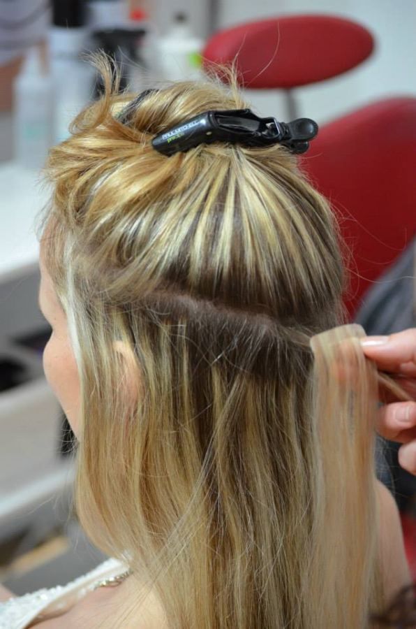Person lässt sich Haarverlängerungen anbringen; blondes Haar, Salon-Atmosphäre.