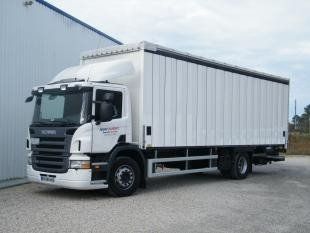 Camion Scania blanc garé à côté d'un bâtiment ; ciel dégagé.