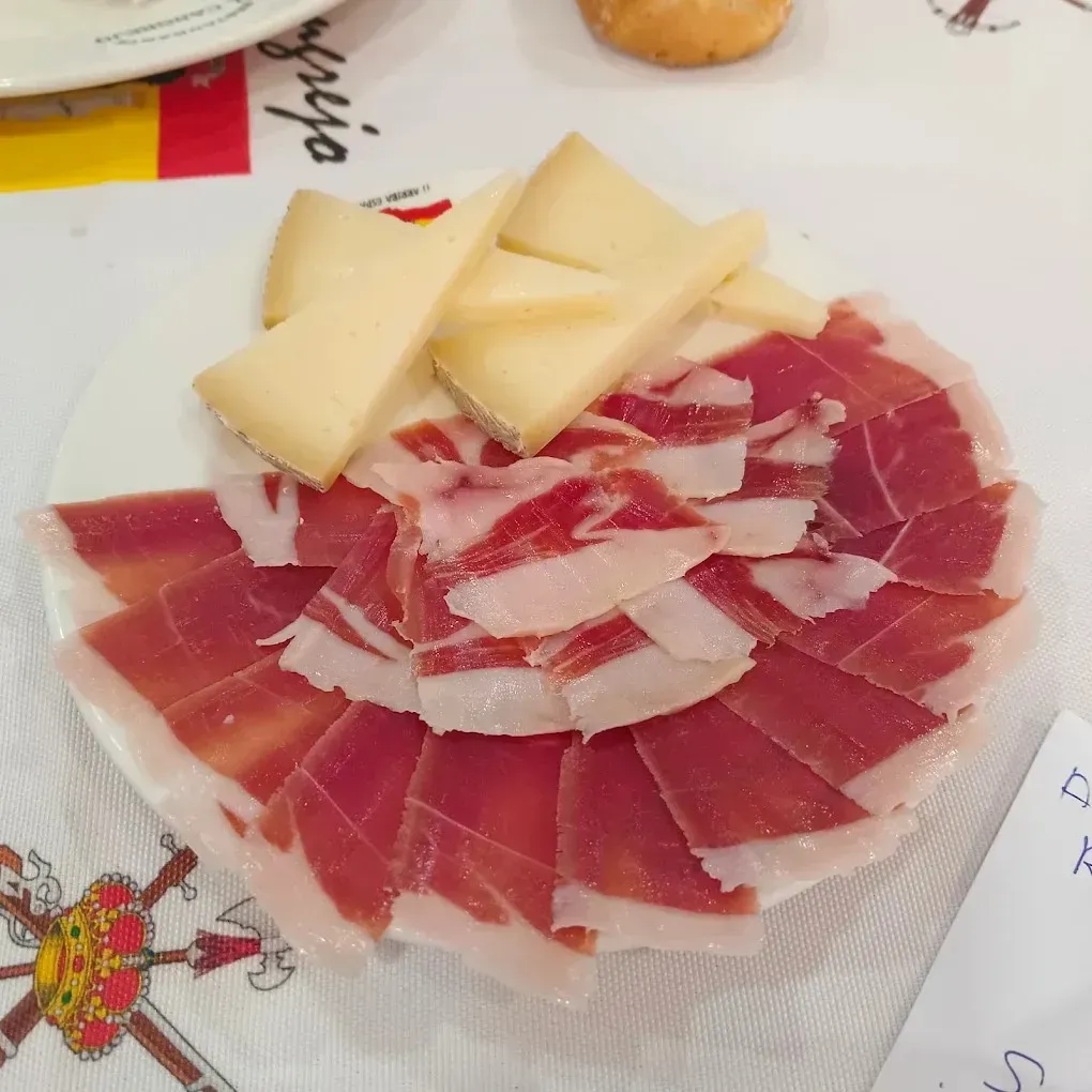 Un plato blanco cubierto con finas lonchas de jamón curado dispuestas en forma de abanico.