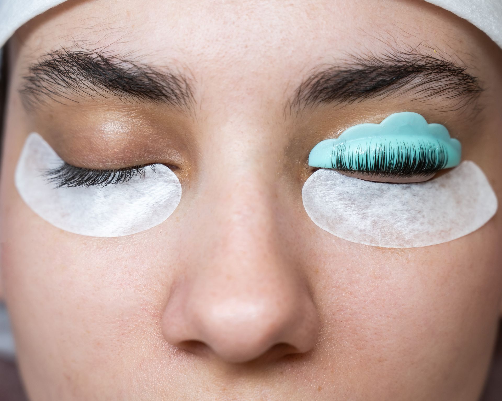 L'œil d'une personne pendant un rehaussement de cils. Un œil a les cils rehaussés, l'autre est protégé par un protège-cils.