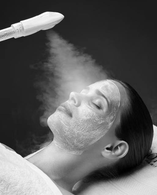 Femme recevant un soin du visage à la vapeur avec application d'un masque facial.