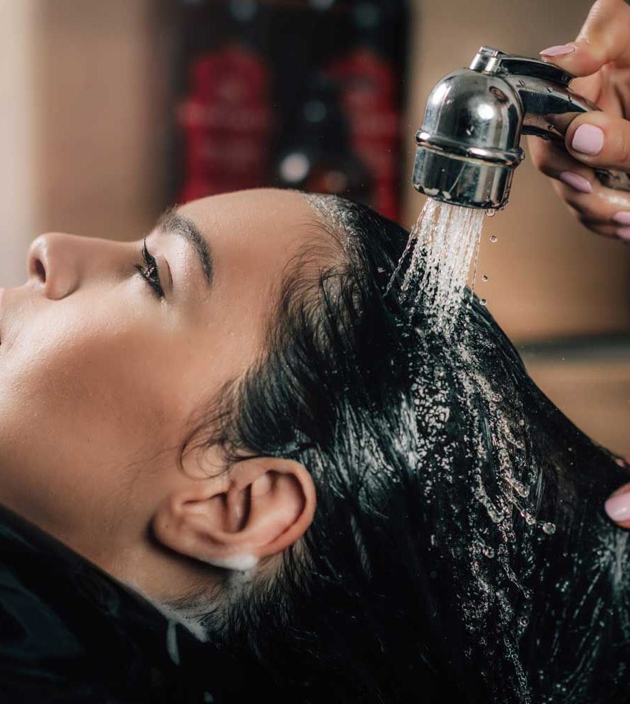 Una mujer se está lavando el cabello en una peluquería.