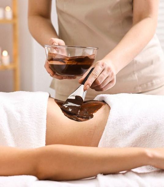 Una mujer está recibiendo un masaje de chocolate en un spa.