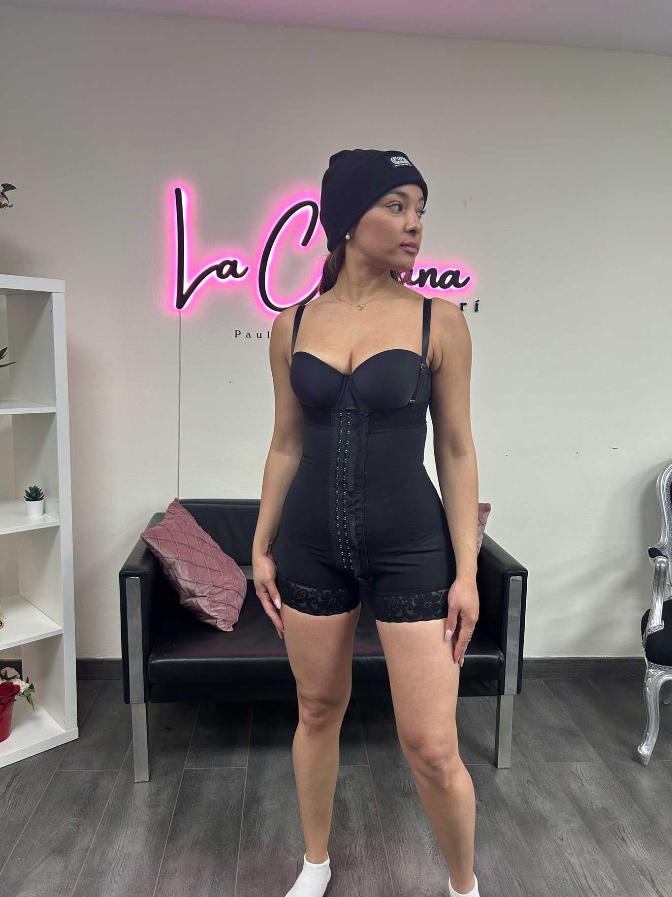 Una mujer con un traje negro está parada frente a una silla.