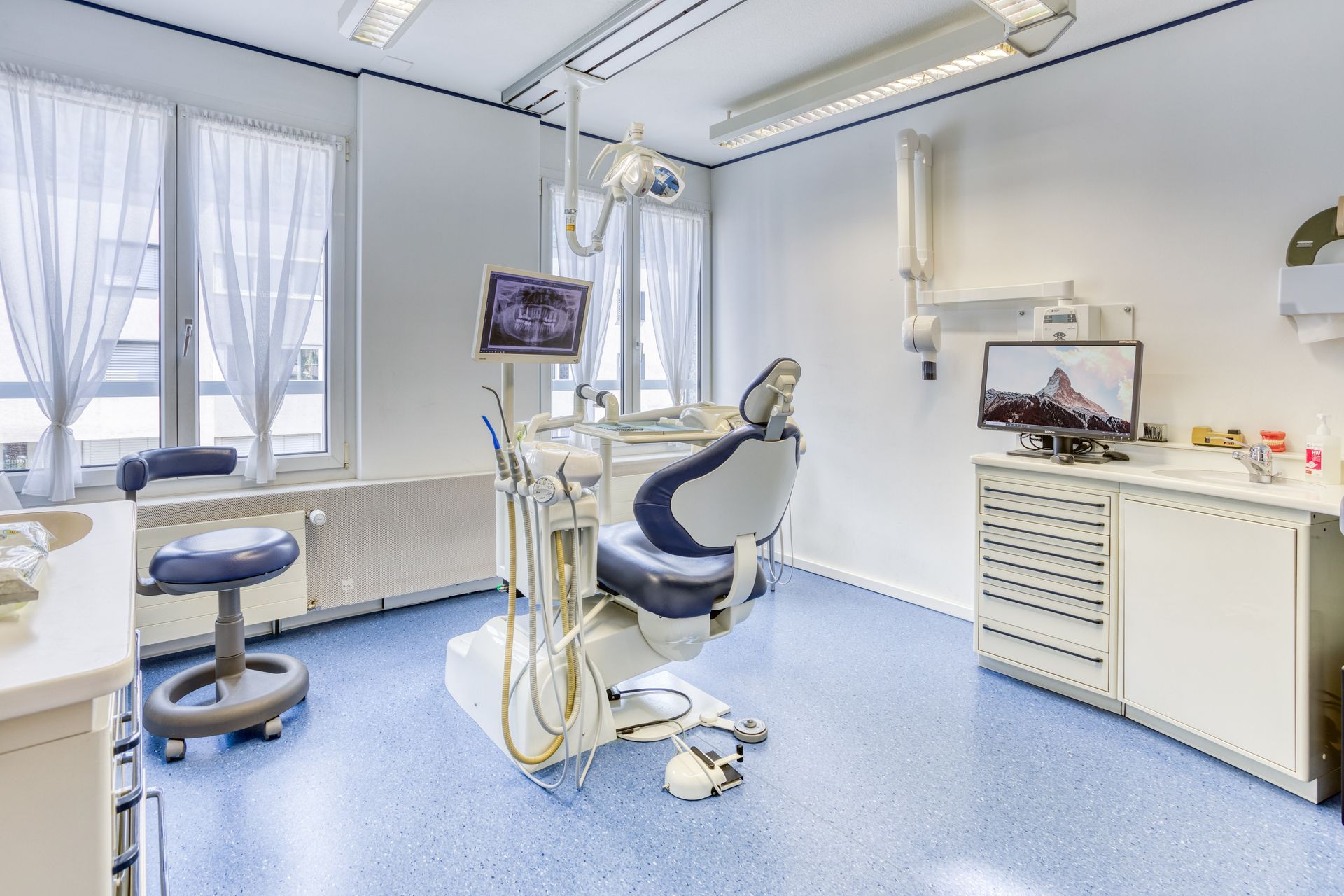 Un cabinet dentaire avec un fauteuil dentaire et un ordinateur.