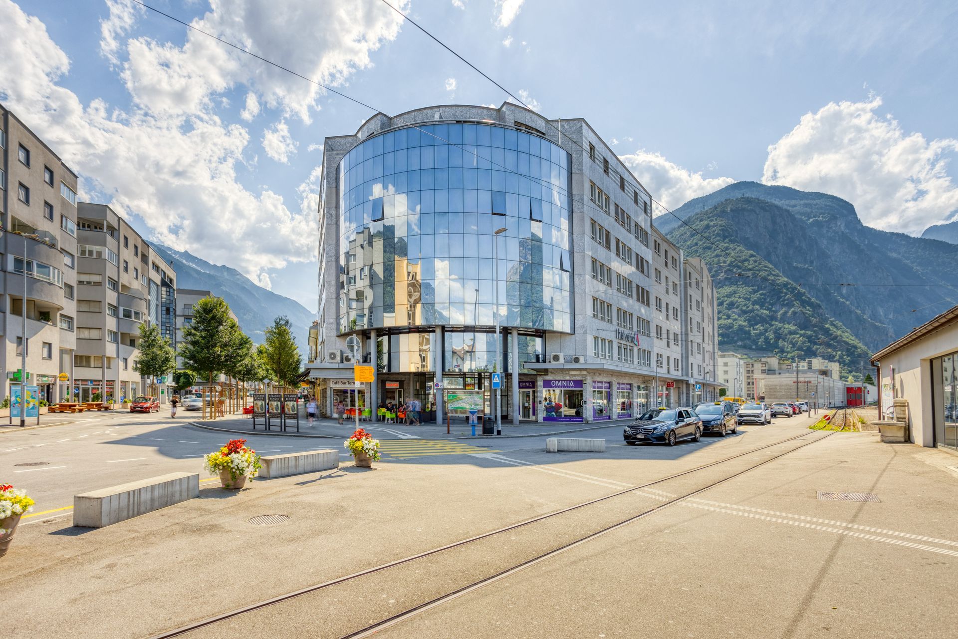 Un grand bâtiment avec beaucoup de fenêtres se trouve au milieu d'une ville avec des montagnes en arrière-plan.